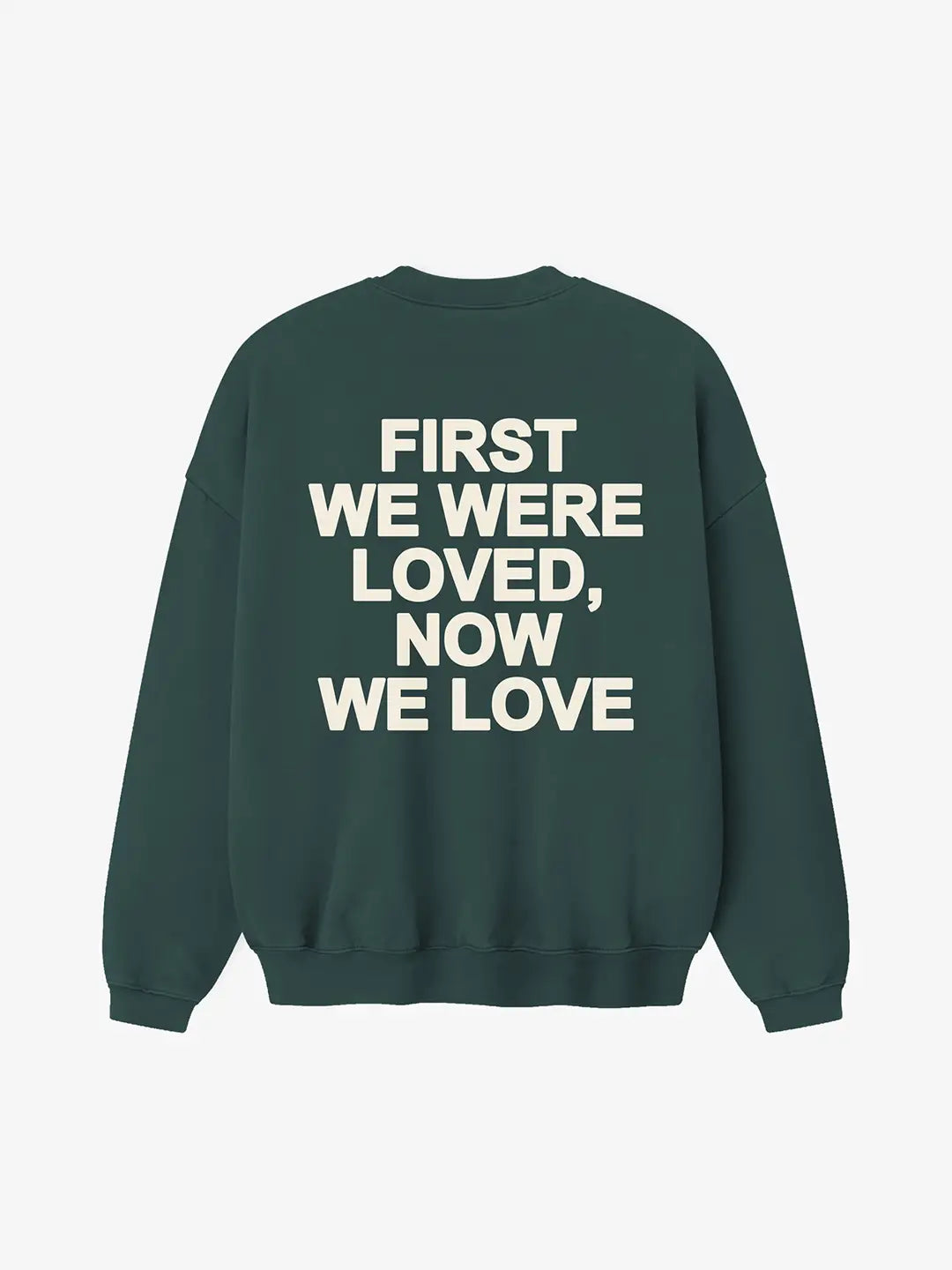 Crewneck oversized WE ARE color verde, vista posterior con estampado “First We Were Loved, Now We Love” en la espalda.