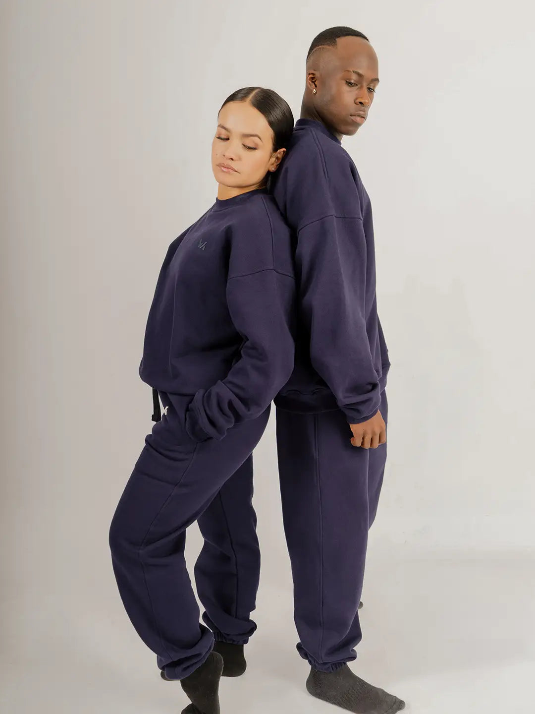 Dos modelos usando crewneck oversized WE ARE color azul marino con jogger a juego, mostrando la silueta relajada y el fit de la prenda.