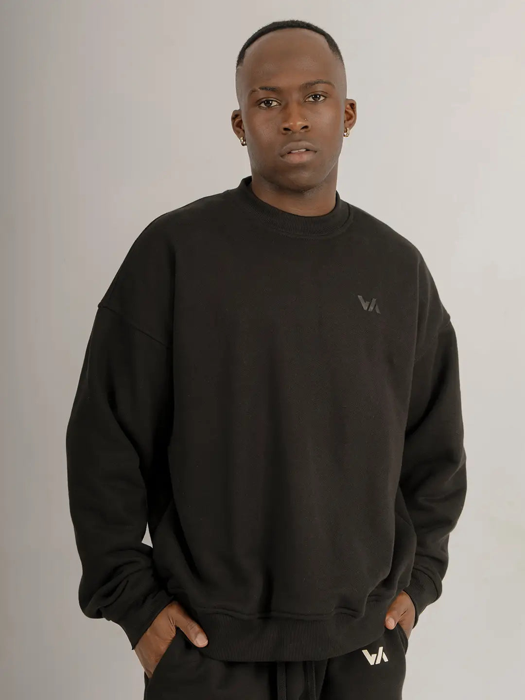 Modelo usando crewneck oversized WE ARE color negro, vista frontal mostrando la silueta, el fit relajado y el logo discreto en el pecho.