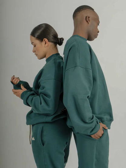 Dos modelos usando crewneck oversized WE ARE color verde con jogger a juego, mostrando la silueta, caída y fit de la prenda.