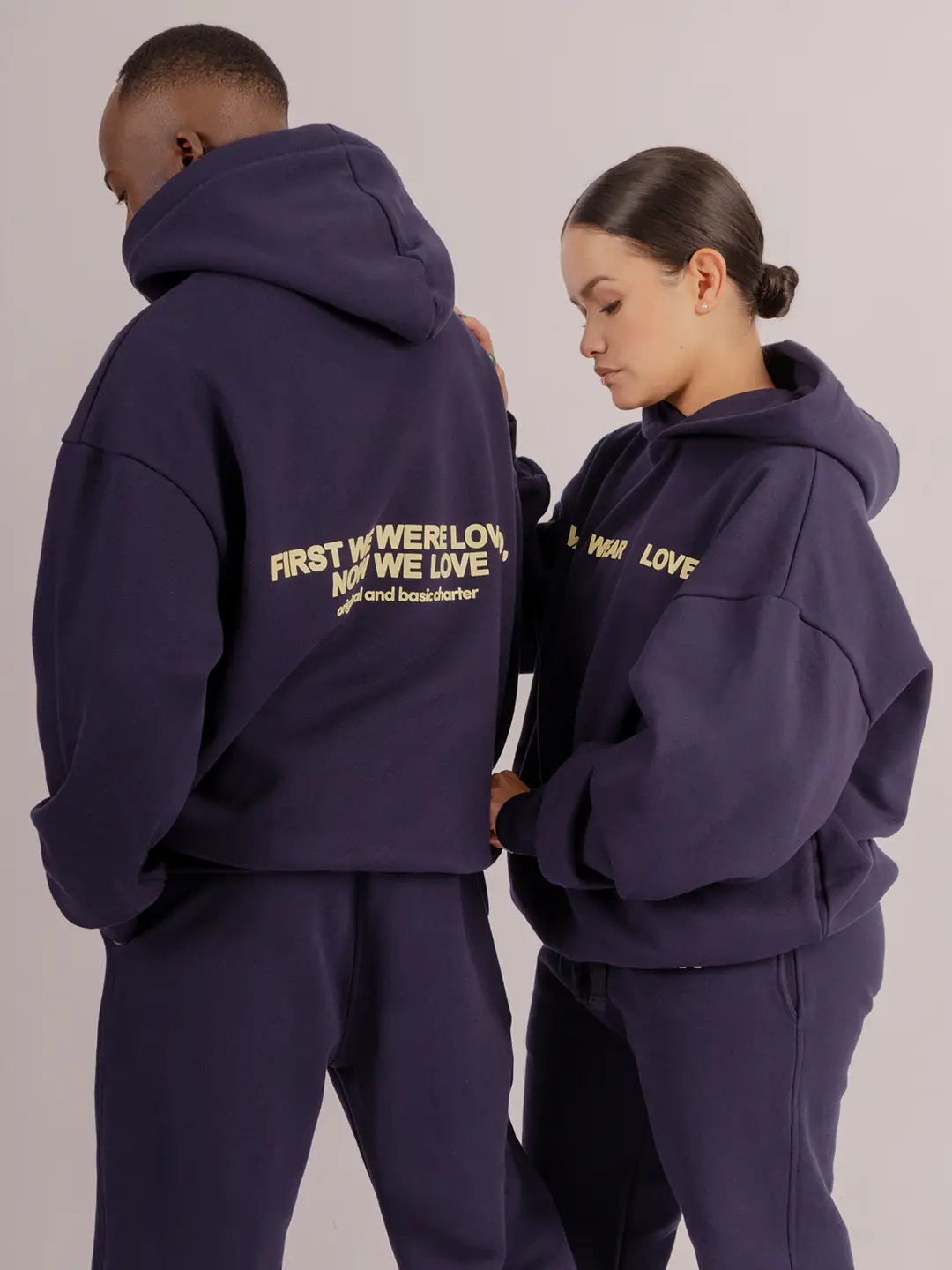 Modelos usando hoodie oversized WE ARE azul marino, vista frontal y posterior.