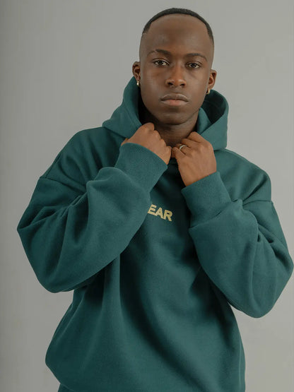 Modelo usando hoodie oversized WE ARE verde, vista frontal mostrando la silueta y el fit.